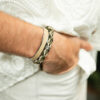 main d'homme dans poche de pantalon avec bracelet leandre vert