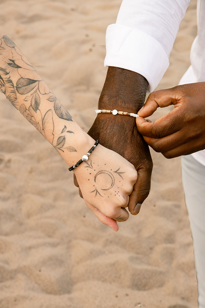 mains d'homme et de femme qui se tiennent, à leur poignets le même bracelet dans 2 couleurs différentes