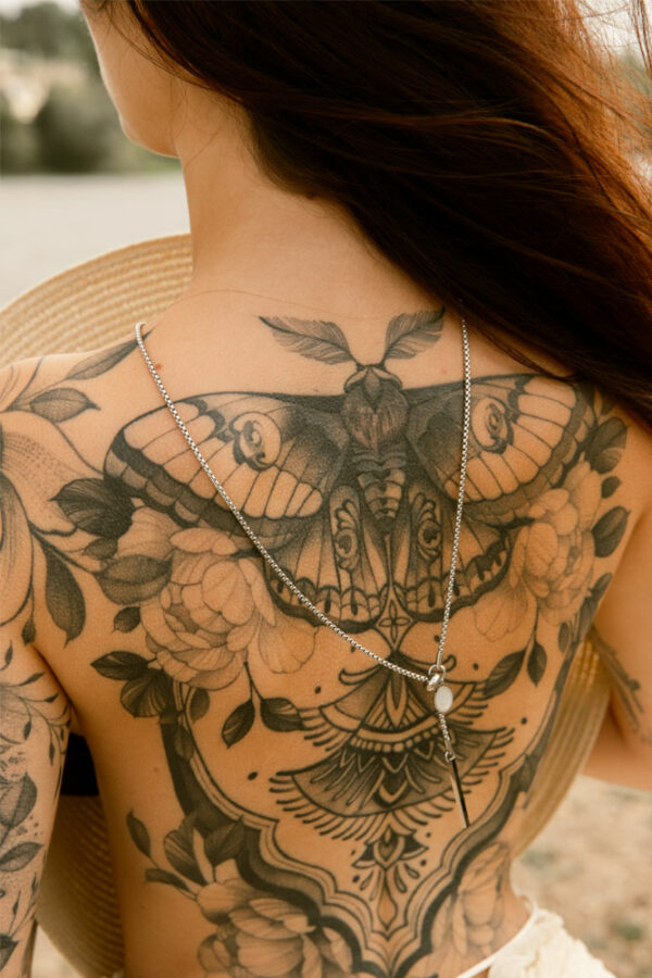 collier longueur réglable en acier inoxydable et nacre blanche porté dans le dos d'une femme tatouée
