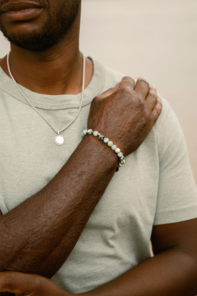 Photo du Photo sur poignet d'homme en t-shirt vert bracelet en agate porté par un homme avec le collier Jill en acier inoxydable et nacre blanche